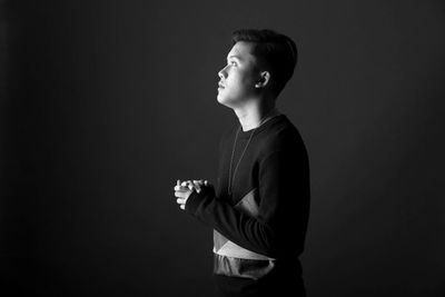 Side view portrait of a boy against black background