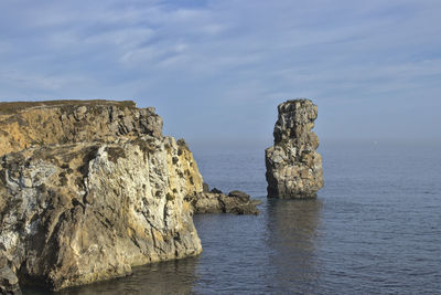 Rock formations by sea against sky