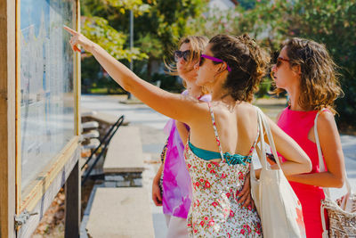 Female tourists reading map while standing on street