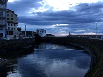 Bridge over river against cloudy sky