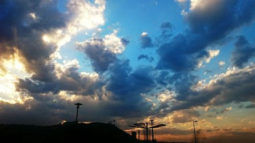 Low angle view of electricity pylon against cloudy sky