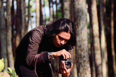 Young woman photographing in forest