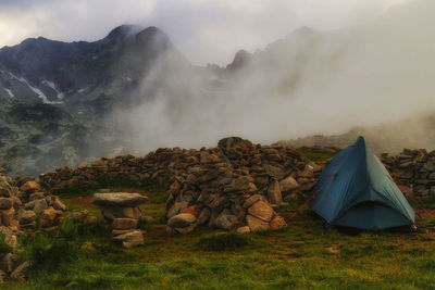 Tent on rocky mountain against sky