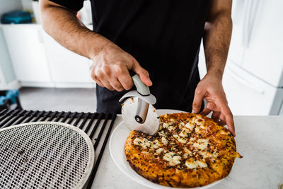 Close up shot of man slicing pizza