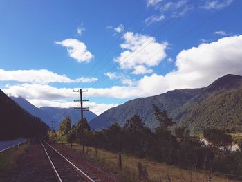 Railroad tracks by mountain against sky