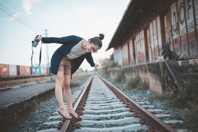 Smiling young woman with camera standing on railroad track