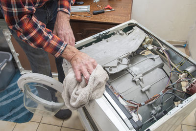 Man is a jack of all trades, he removed the lid of the washing machine and wipes the dust inside