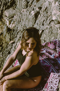 High angle view of woman wearing sunglasses sitting on rock formation