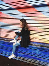 Side view of woman sitting on bench