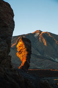 Autumn leaf on rock against sky