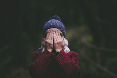 Woman covering face with hands in forest