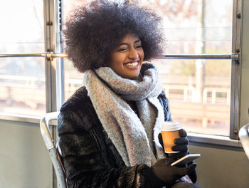 Portrait of young woman drinking coffee in park during winter