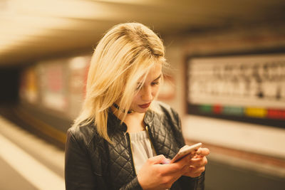 Young woman using mobile phone at train