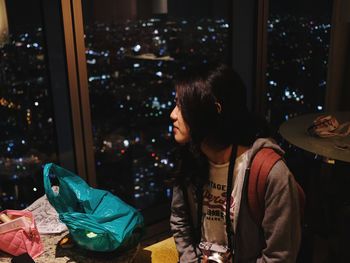 Portrait of woman looking at illuminated city from above