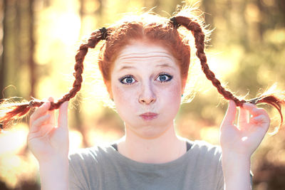 Portrait of woman with puffed cheeks holding pigtail braids