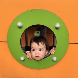 Portrait of cute boy playing against orange wall