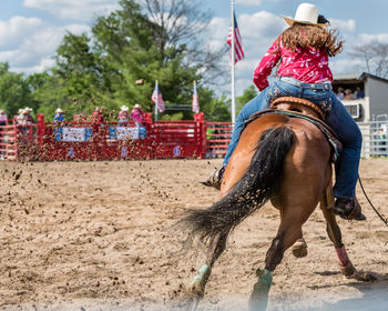 Rear view of female jockey riding horse during race