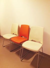 Empty chairs and table against wall