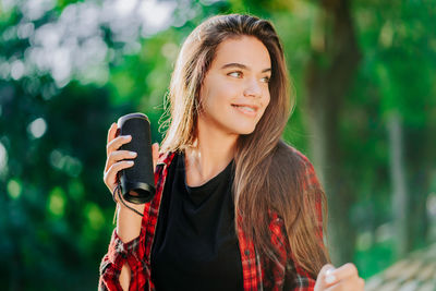 Portrait of smiling young woman holding camera