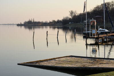 Wooden posts in lake against sky