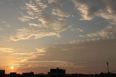 Low angle view of silhouette cityscape against sky