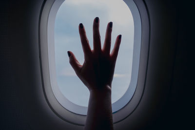 Cropped hand of woman touching airplane window