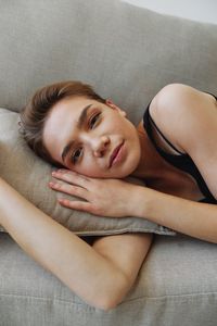 Portrait of young woman lying on sofa at home