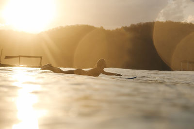 Female surfer in the ocean at sunset