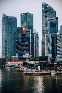 Modern buildings by river in city against sky