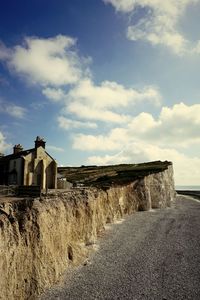 Built structure on landscape against cloudy sky