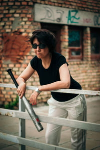 Young woman using mobile phone while standing against railing