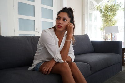 Portrait of young woman sitting on sofa at home