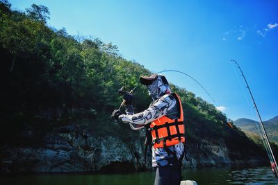 Man standing by river against sky