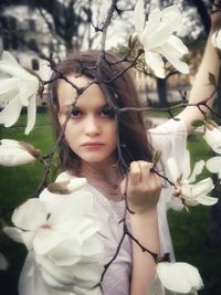 Portrait of a beautiful young woman holding flowering plant