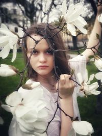 Portrait of girl by white flowers on field