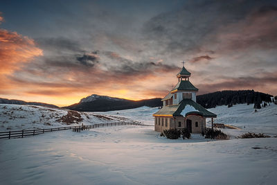 View of cross on snow covered landscape against cloudy sky