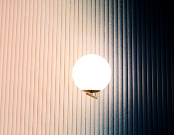 Low angle view of illuminated light bulb on wall