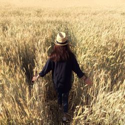 Rear view of woman walking in field