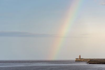 Scenic view of rainbow over sea against sky