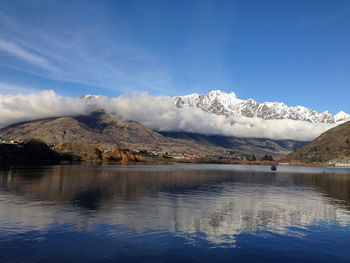 Scenic view of lake and mountains against blue sky