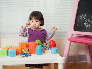 Cute girl standing by blackboard at home