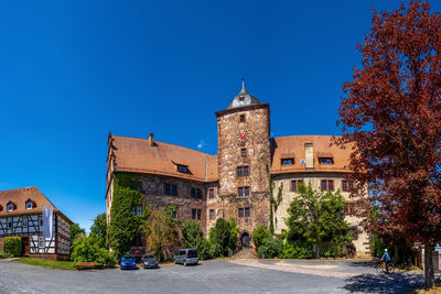 Street amidst buildings against clear blue sky