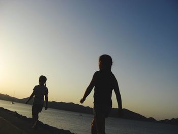 Low angle view of children at beach during sunset