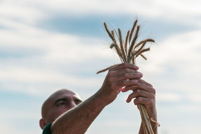 Man holding plants against sky