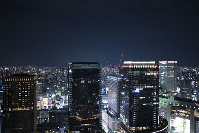 Illuminated buildings in city against sky at night