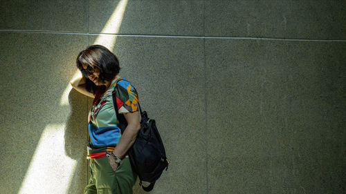 Rear view of woman leaning on the wall 