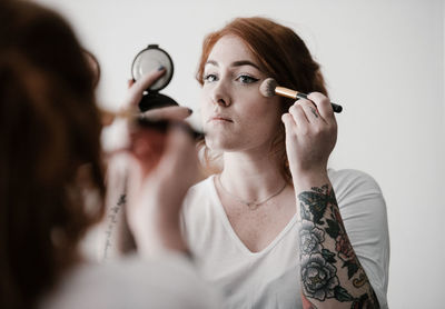 Young woman applying make-up at home