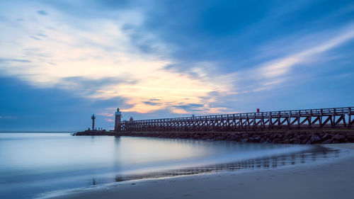 Bridge over sea against sky during sunset