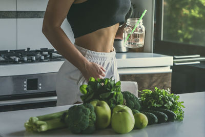 Midsection of woman standing in kitchen at home