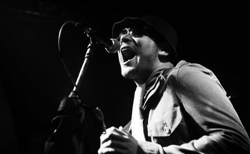 Low angle view of man wearing sunglasses while singing on stage